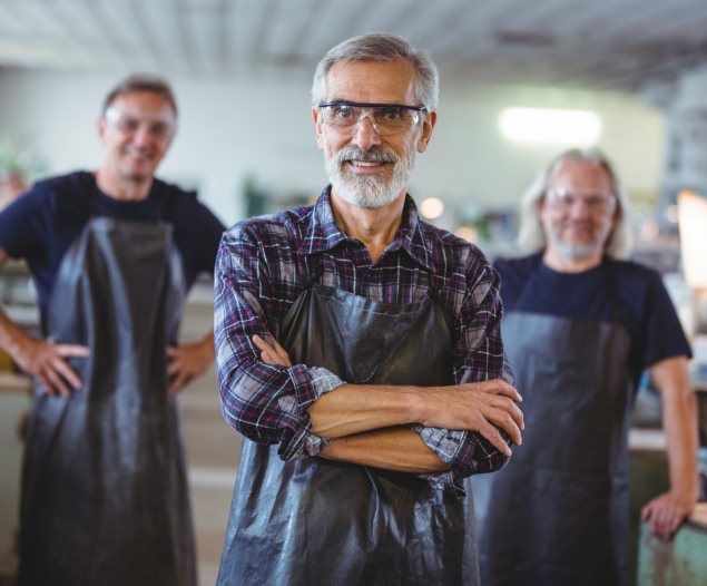 Three glassblowers standing and smiling