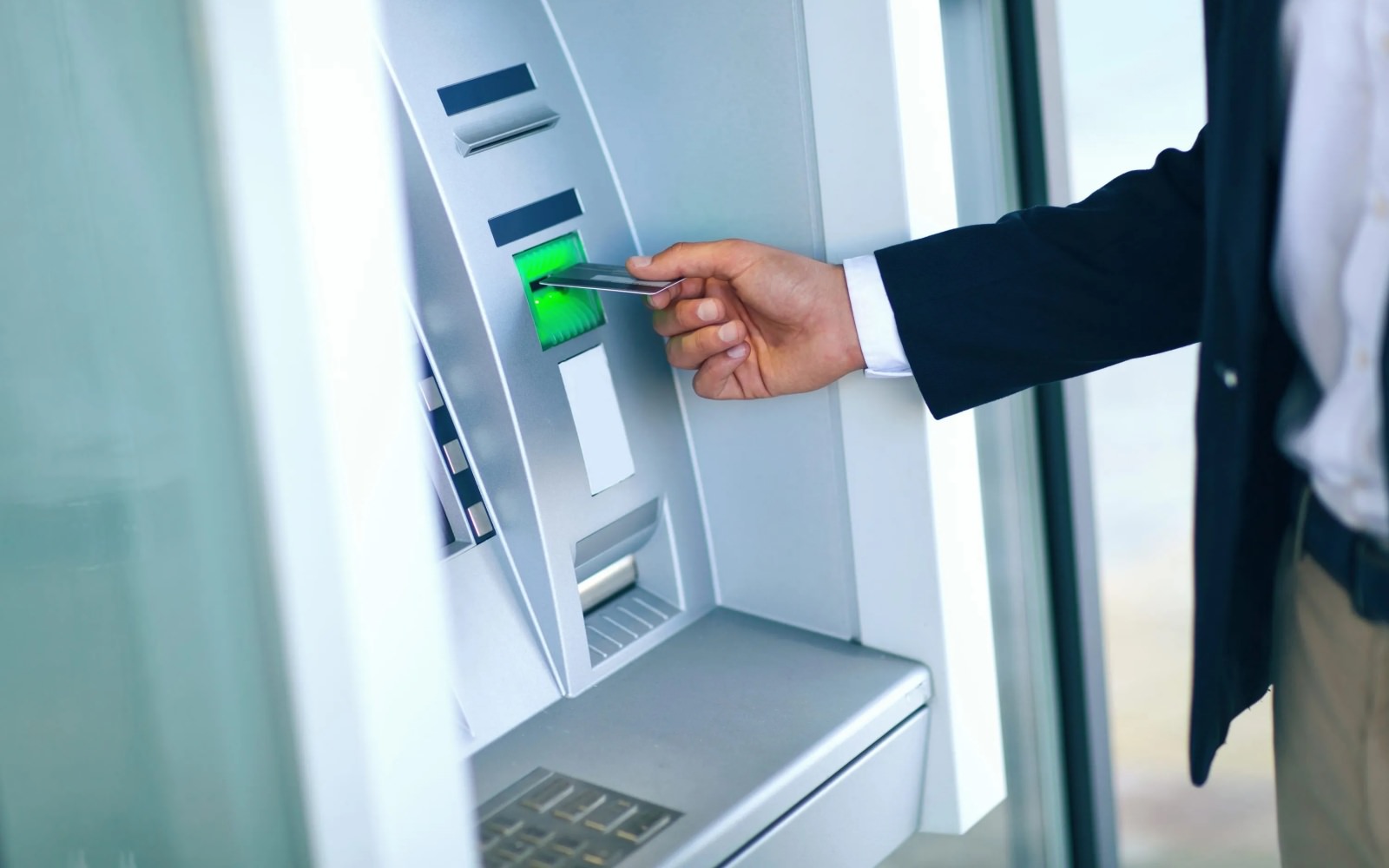 A person inserting their debit card into an ATM